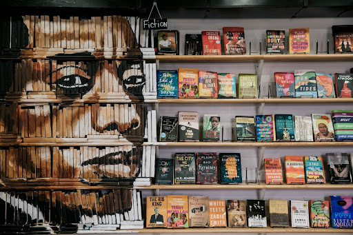 A mural of author James Baldwin painted on the spines of books next to the fiction section in Baldwin & Co.